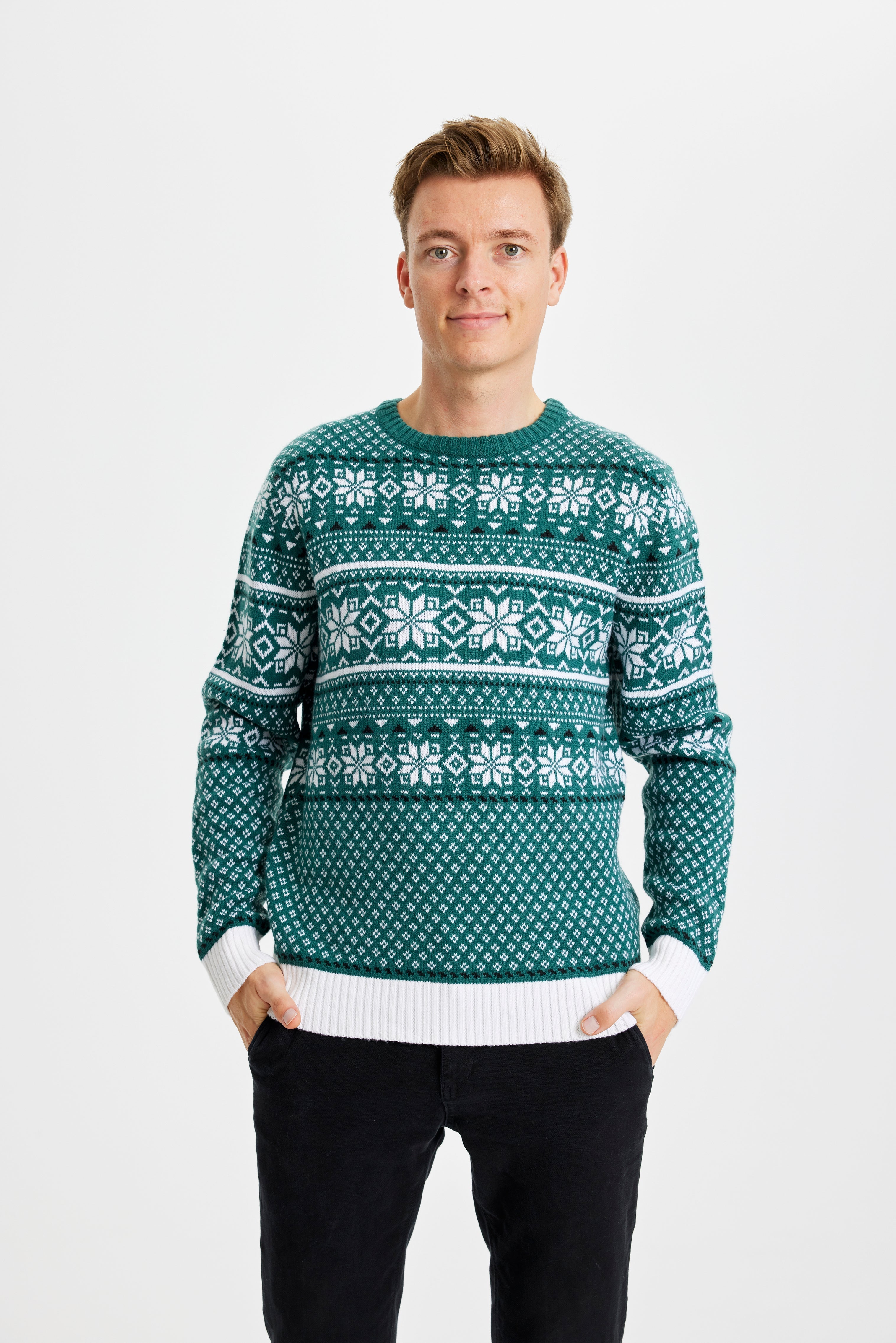 En leende man bär en grön jultröja med snöflingor på.